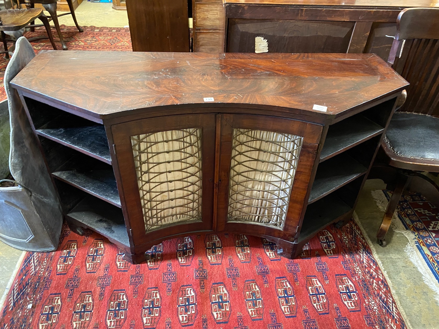 A Regency mahogany side cabinet, the concave centre enclosed by gilt grille doors, width 139cm, depth 50cm, height 76cm